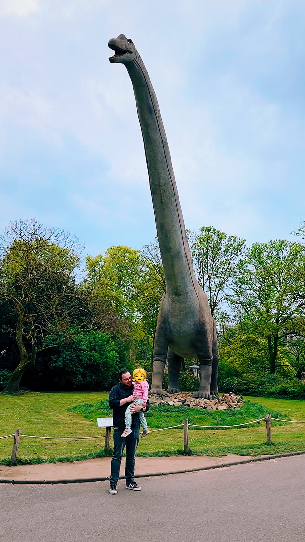 Ariane und ich vor einer riesigen Argentinosaurus-Statue in der grünen Parklandschaft des Kölner Zoos.