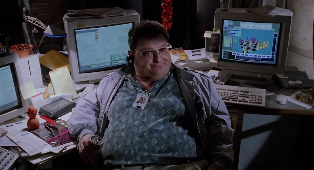 Szene aus Jurassic Park mit Dennis Nedry, der an seinem Schreibtisch vor dem Computer sitzt.