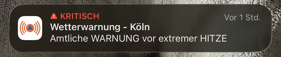 Screenshot einer iPhone-Mitteilung der NINA-Warn-App mit roter Kennzeichnung „KRITISCH“. Die Benachrichtigung trägt den Titel „Wetterwarnung – Köln“ und informiert über eine „Amtliche WARNUNG vor extremer HITZE“.